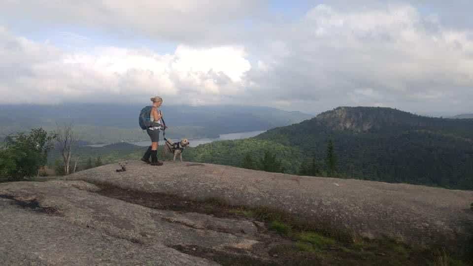 Une femme fait une randonnée avec son chien dans les Laurentides.