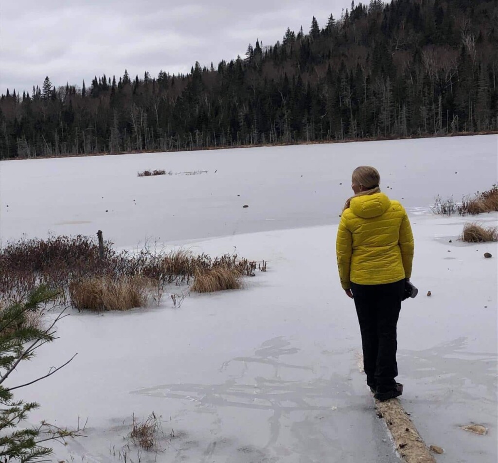 Une femme portant un manteau jaune qui observe le paysage hivernal dans Lanaudière.