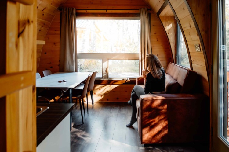 Vue sur la salle à manger, le coin salon et la grande fenêtre du chalet à louer Pod, un hébergement insolite à Saint-Fulgence, au Saguenay-Lac-Saint-Jean