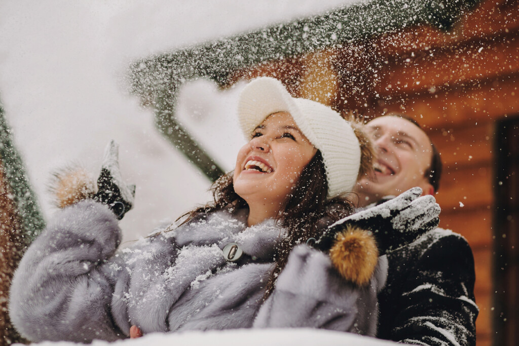 Un couple souriant, heureux de voir la neige, lors de leur escapade en amoureux dans un chalet.