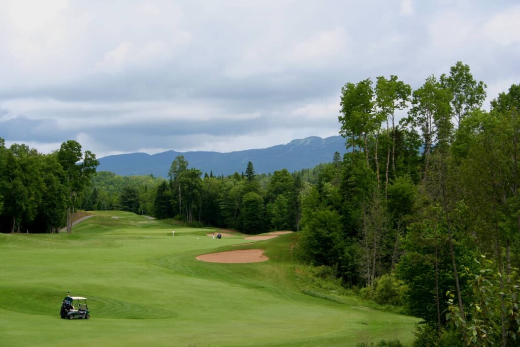 Voiturette et golfeurs foulant un magnifique parcours de golf à Mont-Tremblant.