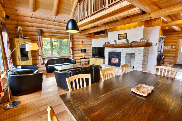 Table à manger et salon avec foyer au bois du chalet à louer Chalet les Marmottes dans la région de Québec, chalet bord de l'eau à Sainte-Christine-d'Auvergne.