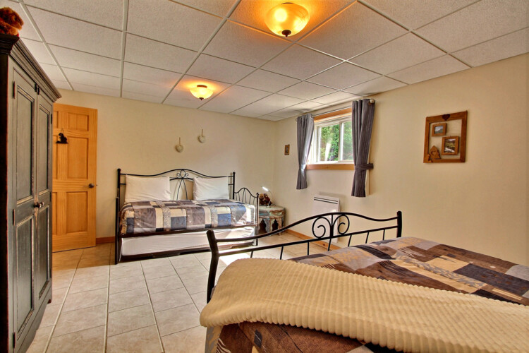 Chambre avec plusieurs lits du chalet à louer Chalet les Marmottes dans la région de Québec, chalet bord de l'eau à Sainte-Christine-d'Auvergne.