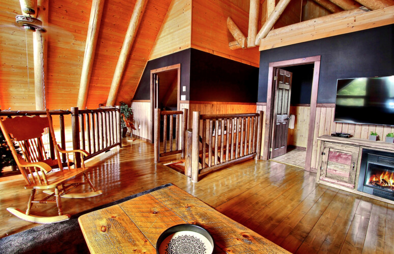Salon à la mezzanine avec foyer du chalet à louer Chalet la Tanière dans la région de Québec, chalet bord de l'eau à Sainte-Christine-d'Auvergne.