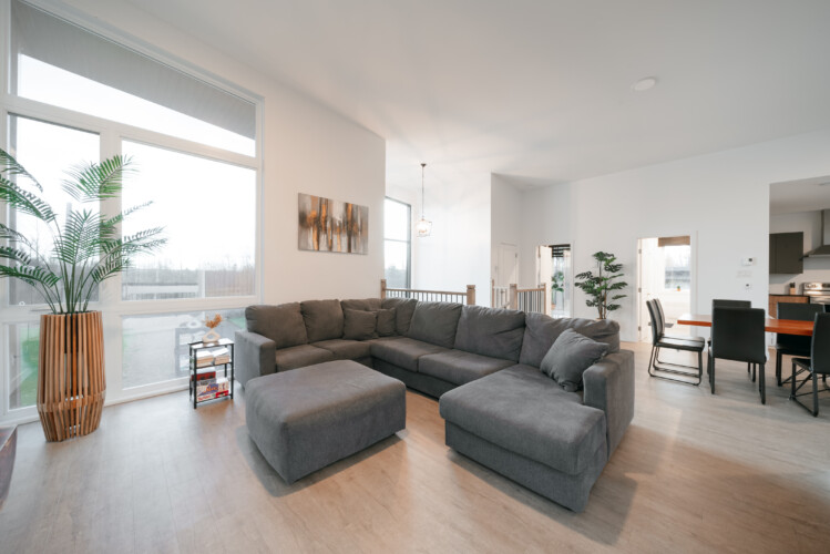 Sofa sectionne en tissus gris du chalet en location Le Mëlyā en Estrie, chalet avec foyer au bois à Weedon.