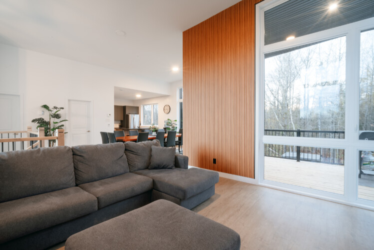 Sofa avec vue sur le balcon du chalet à louer Le Mëlyā en Estrie, chalet avec foyer au bois à Weedon.