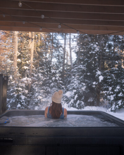 Femme dans le spa en hiver du Chalet en location Saïra à Lanaudière, chalet avec spa et sauna à Notre-Dame-de-la-Merci.