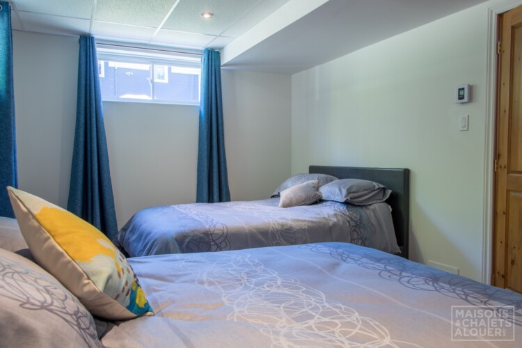 Chambre avec 2 lits décorés de couette de couleur bleu-gris du Chalet à louer Le Grand Duc en Estrie, chalet au bord de l'eau avec spa à Lambton.
