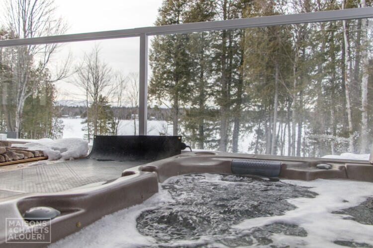 Jacuzzi fumant en hiver du Chalet en location Le Grand Duc en Estrie, chalet au bord de l'eau avec spa à Lambton.